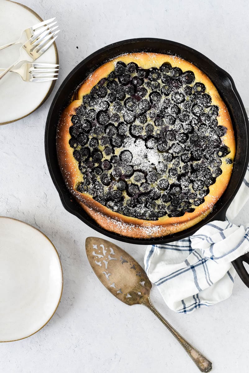 overhead view of blueberry clafoutis with napkin and serving utensils
