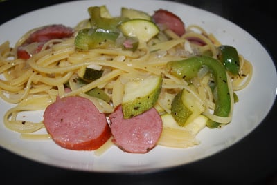 A plate of food, with Kielbasa and Linguine and zucchini