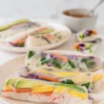 fresh rainbow veggie spring rolls on white plates with peanut dipping sauce