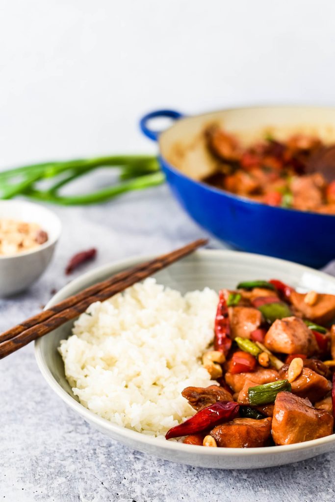 plate with rice and chicken in front of cooking pan