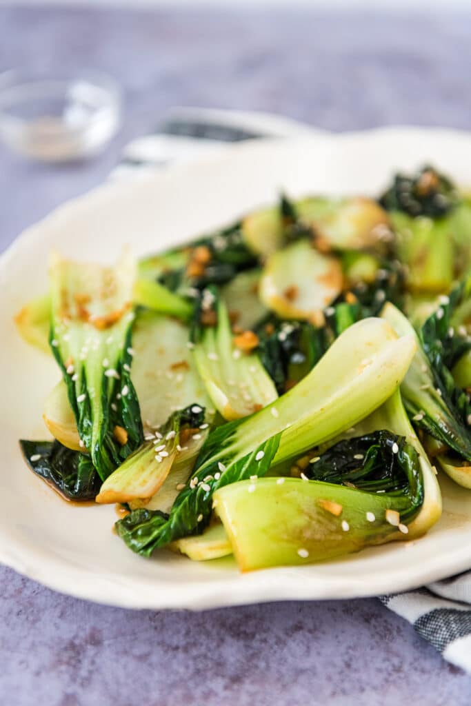 baby bok choy stir fried in sesame, garlic and soy sauce on a white platter